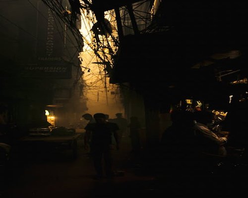 A person walking down a quiet Dhaka street in the evening